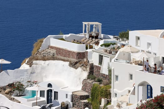 Oia, Santorini, Greece - July 3, 2021: Whitewashed houses with terraces and pools and a beautiful view in Oia on Santorini island, Greece