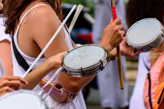 Woman playing tambourine in crowded brazilian streets during carnival festivities