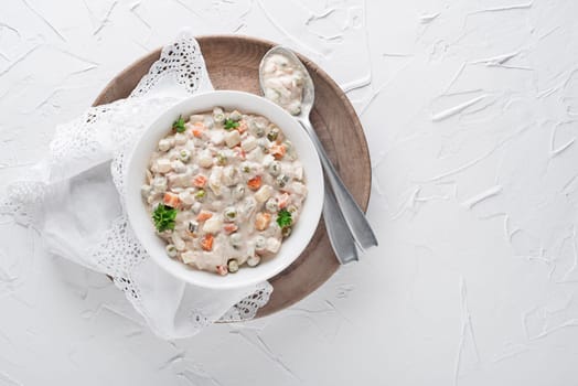 Bowl of russian salad olivier french salad with vegetables and egg dressed with mayonnaise on white table