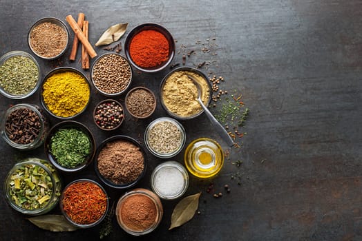 Colorful herbs and spices for cooking. Indian spices. On grey stone background. Top view.