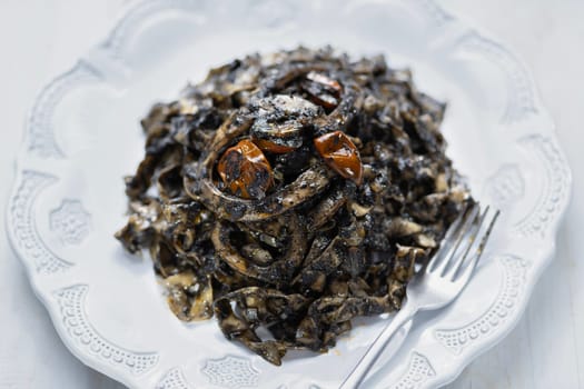 close up of plate of squid ink tagliatelle pasta