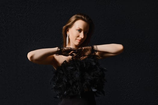 Low key photo of cute woman in corset with feathers and in fatin gloves