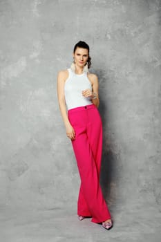 Trendy woman standing over grey background and looks suspicious