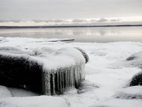 Ice icicles hanging down. Northern arctic winter season. Frozen nature. Retro or vintage style. Black and white image. Frozen water on the lake. Karelia, Russia, December 2020. Lake Onega.
