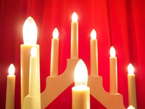 Schwibbogen arch luminaire in the form of a triangular candlestick. Red background. Evening, romantic, festive, religious or mystical atmosphere. Burning light bulbs or candlelight. Double exposure