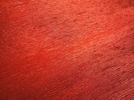 Corrugated paper in red. Uneven surface. Abstract background. Wavy edges of the paper sheet. Lighting gradient.