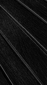 black abstract background with stripes diagonally, vertical image. Wooden monochrome texture.