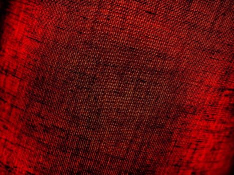 Red abstract background made of fabric. Macro image. Weaving tap-colored pits with black shadows and vignettes. Background for Christmas, New Year, Valentine's Day.