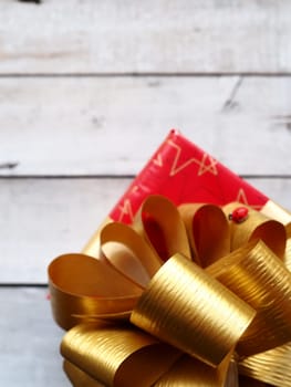 Red gift box with a large gold bow on a wooden background painted with white paint. Gift for Christmas, New Year, Birthday, Mother's Day, Wedding, Valentine's Day. Beautiful festive decoration.