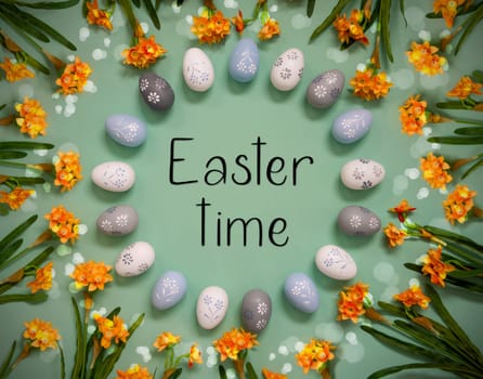 Flat Lay With English Text Easter Time. Easter Egg Decoration With Orange Spring Flowers. Light Green Paper Background With Bright And Shiny Light Effect.
