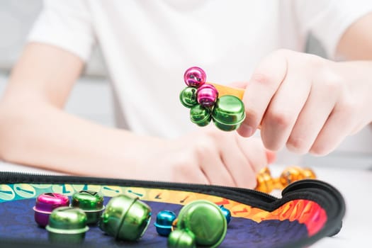 Little kid play toy sitting at table closeup. Hand of child magnetize and pick up colorful metal playthings from plate. Home leisure, funny playtime. Entertaining interesting board game.