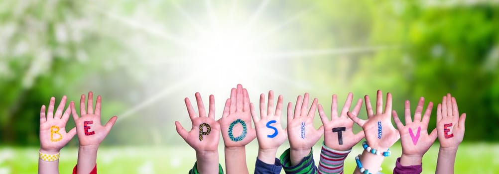Children Hands Building Colorful English Word Be Positive. Sunny Green Grass Meadow As Background.