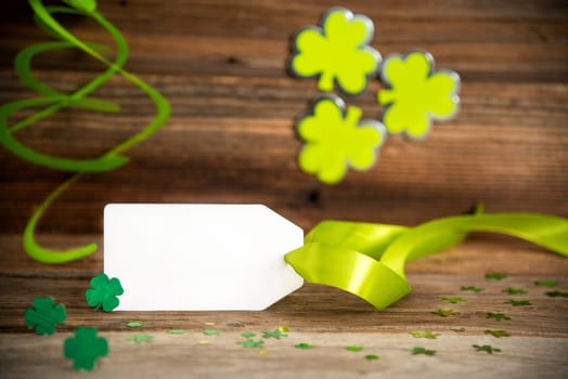 White Label With Copy Space. Saint Patrick's Day Decoration With Green Shamrock And Clover. Wooden Vintage Background With Festive Ribbon.