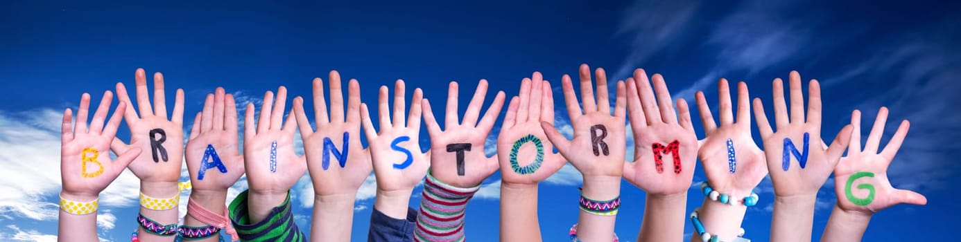 Children Hands Building Colorful English Word Brainstorming. Blue Sky As Background