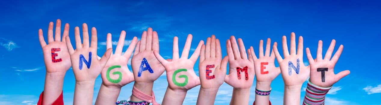 Children Hands Building Colorful German Word Engagement Means Commitment. Blue Sky As Background