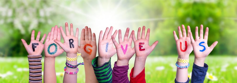 Children Hands Building Colorful English Word Forgive Us. Sunny Green Grass Meadow As Background