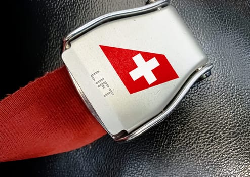 Zurich, CH Jan 2023: detail of the buckle of the seat belt with the logo of Swiss Air on an empty seat. Swiss Air is the flag carrier of Switzerland. Illustrative editorial. Safe travel