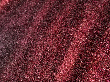 Bokeh light of pink glitters on black background. Magenta glitter texture. Sparkling glitter wrapping paper with sequins and sparkles. Festive purple bokeh and glitter. Diagonal stripes and waves.
