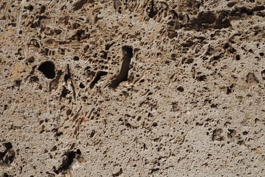 Textured wall lined with beige shell rock tiles. Close-up of a wall made of ancient shell rock. Holes, irregularities of natural building material. Church wall in Banja Koviljaca, Serbia.