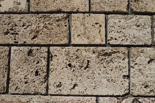 Textured wall lined with beige shell rock tiles. Close-up of a wall made of ancient shell rock. Holes, irregularities of natural building material. Church wall in Banja Koviljaca, Serbia.