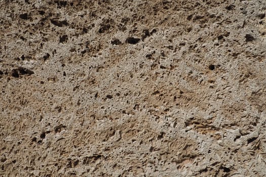 Textured wall lined with beige shell rock tiles. Close-up of a wall made of ancient shell rock. Holes, irregularities of natural building material. Church wall in Banja Koviljaca, Serbia.