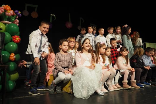Sremska Mitrovica, Serbia March 8, 2022 Children's choir performance on stage. Children sing. Musical children's group in elegant costumes perform holiday songs for mothers. Dark scene