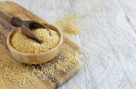 Raw Dry bulgur wheat grain in a wooden bowl with a scoop close up, copy space. Vegetarian and Vegan, Mediterranean and Middle Eastern cuisine. Healthy lifestyle