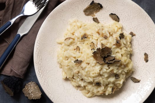 Risotto with wild porcini mushrooms and black truffles from Italy served in a plate top view on white table, copy space. Eating Italian gourmet cousine