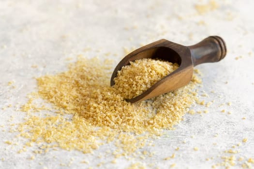 Wooden scoop of Dry uncooked bulgur wheat grain close up, copy space. Vegetarian and Vegan, Mediterranean and Middle Eastern cuisine. Healthy lifestyle