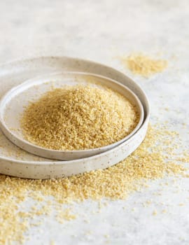 Raw Dry bulgur wheat grain on a white plate on a table close up, copy space. Vegetarian and Vegan, Mediterranean and Middle Eastern cuisine. Healthy lifestyle