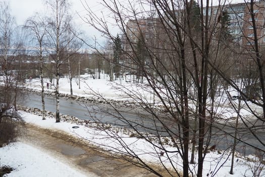 Petrozavodsk, Karelia, Russia January 15, 2023. Snowdrifts on roadsides. Sidewalk covered with sand. Bare trees. Winter cloudy day. Wet asphalt road in the thaw. Kemskaya street, Klyuchevaya district