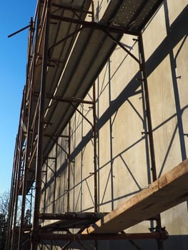 Scaffolding on a new one-story house. Facade works. Building bussiness. Low-rise private building. Plastering the wall of a building. Shop building. Metal production structures