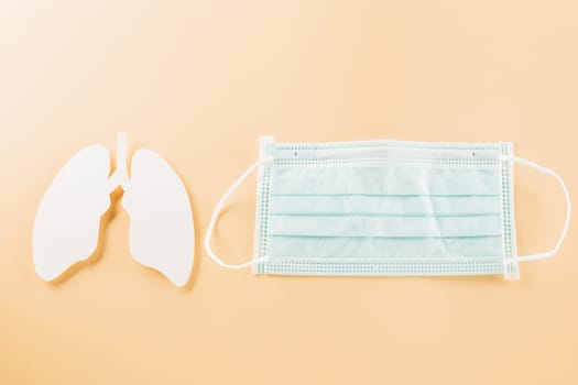 World TB Day. Overhead lungs paper symbol and facial medical face mask on pastel background, lung cancer awareness, copy space concept of world tuberculosis day, banner background