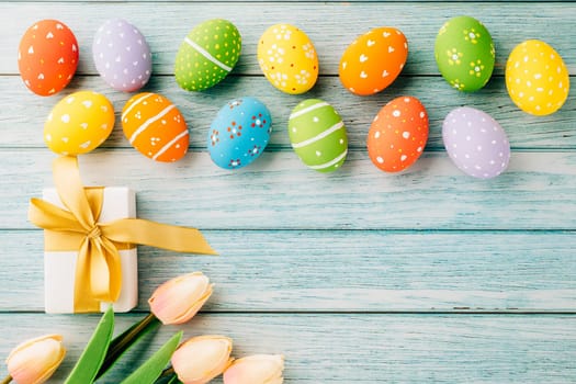 Happy Easter Day. Top view holiday banner background design with easter colorful eggs and gift box on blue wooden background with copy space