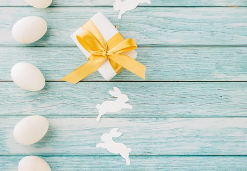 Happy Easter Day. Top view holiday banner background design with easter white eggs and gift box on blue wooden background with copy space