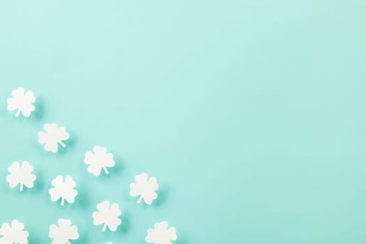 Saint St Patrick's Day. Top view flat lay of paper cut clover leaves festive decor, shamrocks leaf holiday symbol with copy space on colour background, Banner greeting card good lucky concept