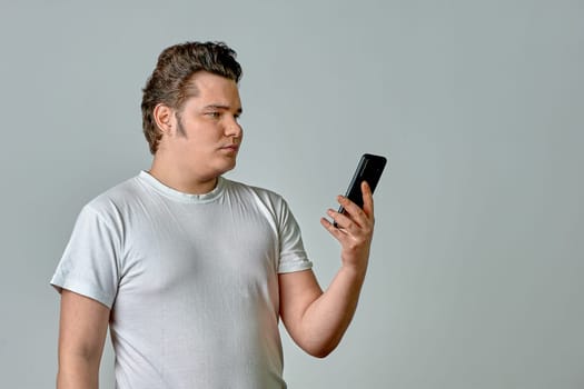 a man on a light background looks at the phone. High quality photo