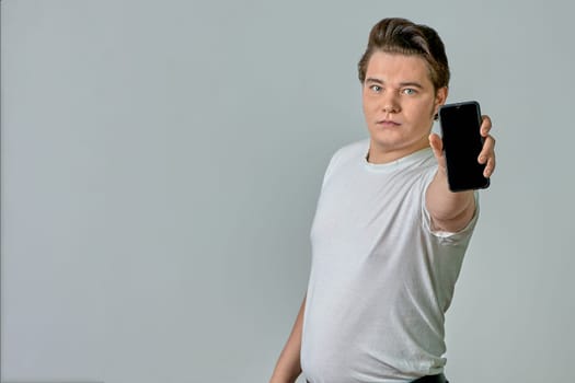 A man at arm's length shows a phone screen on a gray background. High quality photo