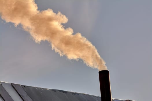 smoke is coming from the chimney of the bourgeoisie. the stove is being heated. High quality photo