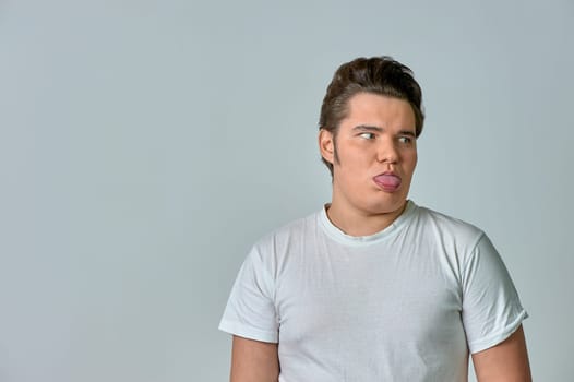 a man on a gray background shows his tongue. High quality photo