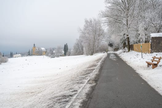 Neunkircher hoehe near darmstadt during winter with lots of snow and yellow church in the background, cloudy day, germany