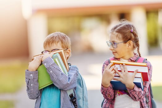 Girl and boy in glasses standing with books in their hands. Concept of back to school and studying.
