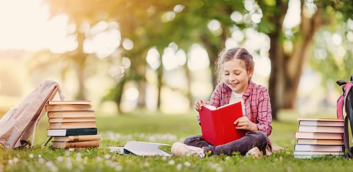 Loneliness girl sitting on the green meadow and readung a book. Concept of hobby and studying.