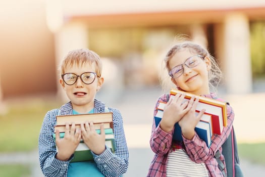 Girl and boy in glasses standing with books in their hands. Concept of back to school and studying.