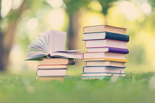 Stack of the books standing on the green meadow outdoors. Concept of the family vacation, hobby and reading.