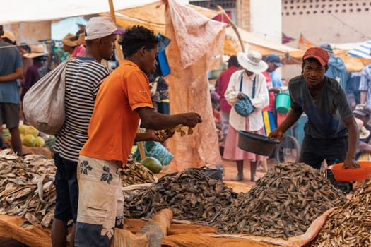 Mandoto, Madagascar - November 9. 2022 - Malagasy man buys dried fish at a street market. Fishing is one of the livelihoods in Madagascar.