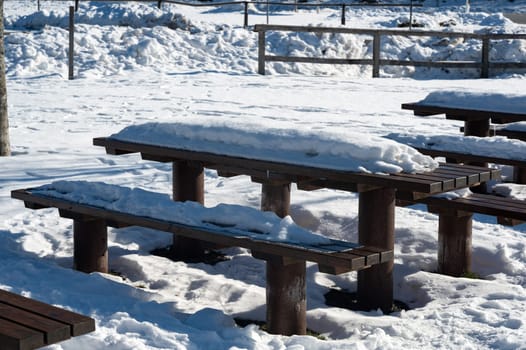 Park bench and table with lots of snow on a cold winter day