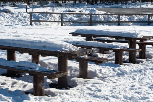 Park bench and table with lots of snow on a cold winter day