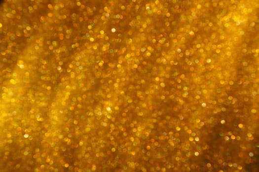 Bokeh light of gold glitters. Golden glitter texture background. Sparkling glitter wrapping paper with sequins and sparkles. Festive golden bokeh and glitter. Diagonal stripes and waves.