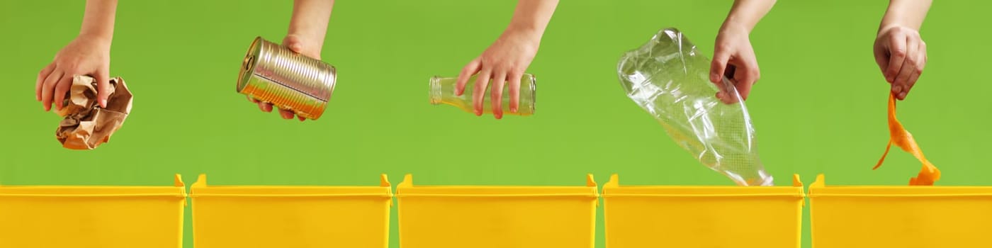 Children's hands throw paper, metal, glass, plastic, organic garbage into different yellow containers on a light green background. Waste sorting. Environment care. Recycling and ecology concept.